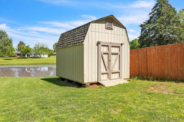 view of shed with fence and a water view