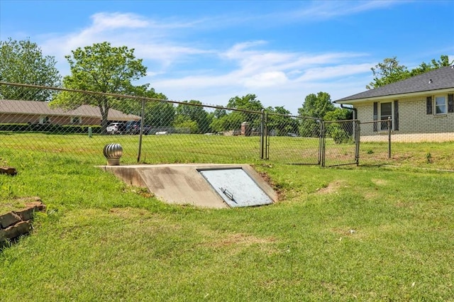 entry to storm shelter featuring a gate, fence, and a yard