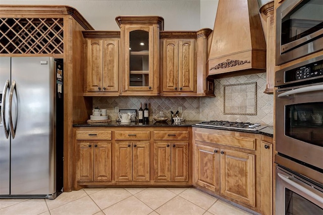 4495 SE 37th St, Norman, OK 73072 - kitchen with appliances with stainless steel finishes, premium range hood, backsplash, and glass insert cabinets