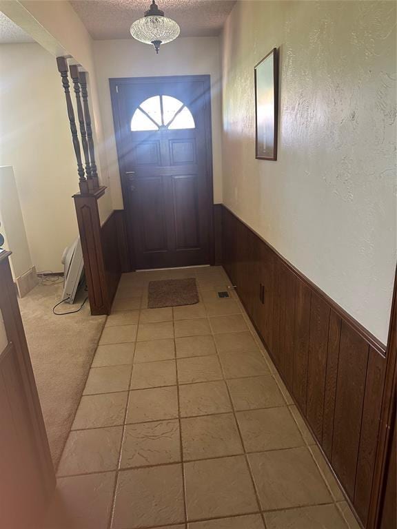 1721 E Ridgeview Ter, Mustang, OK 73064 - doorway to outside with wood walls, a textured ceiling, a wainscoted wall, and light tile patterned flooring