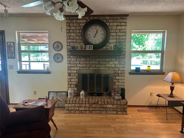 1721 E Ridgeview Ter, Mustang, OK 73064 - living room featuring visible vents, a brick fireplace, wood finished floors, ceiling fan, and a textured ceiling