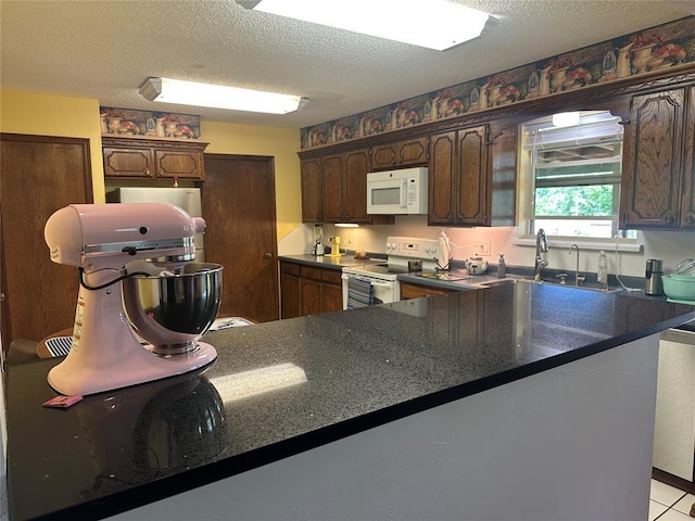 1721 E Ridgeview Ter, Mustang, OK 73064 - kitchen with white appliances, a textured ceiling, dark brown cabinetry, and a sink