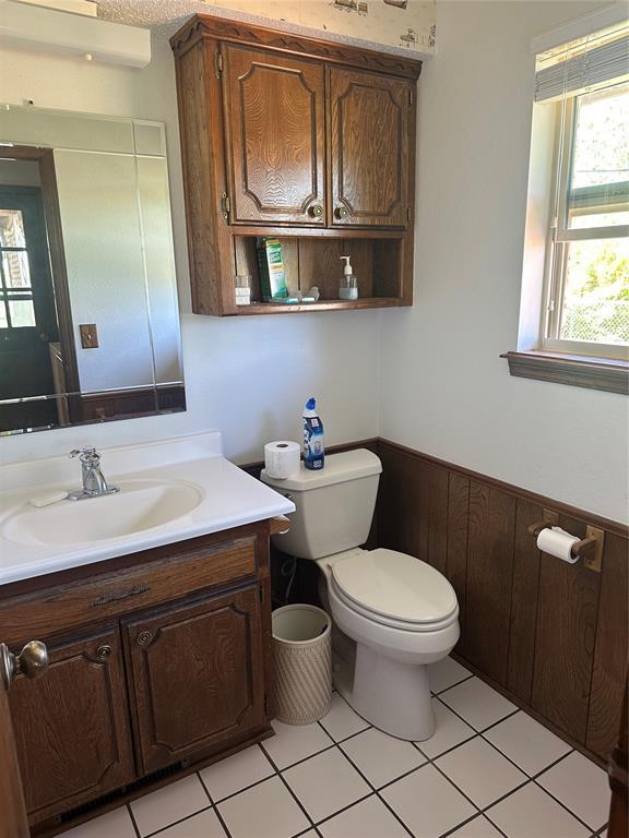 1721 E Ridgeview Ter, Mustang, OK 73064 - half bathroom featuring vanity, tile patterned floors, a wainscoted wall, and toilet
