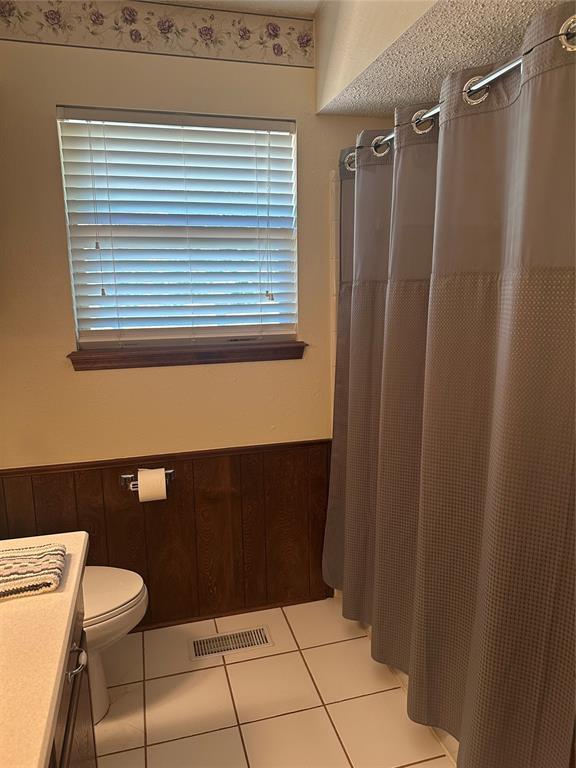 1721 E Ridgeview Ter, Mustang, OK 73064 - bathroom featuring a wainscoted wall, tile patterned floors, and visible vents