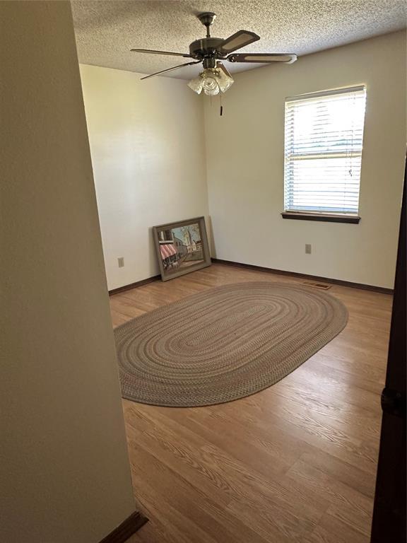 1721 E Ridgeview Ter, Mustang, OK 73064 - spare room with baseboards, a textured ceiling, ceiling fan, and wood finished floors