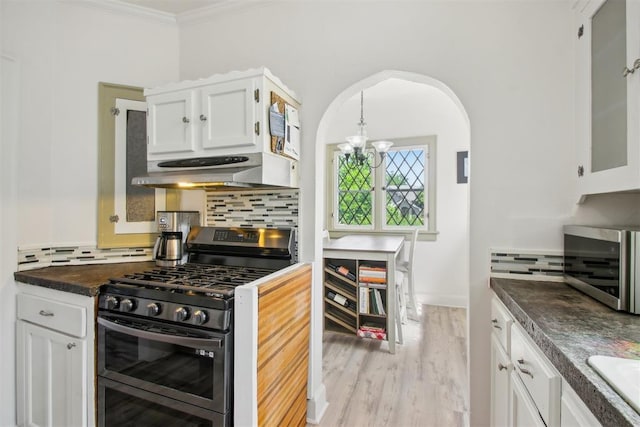 1912 NW 22nd St, Oklahoma City, OK 73106 - kitchen with stainless steel appliances, under cabinet range hood, arched walkways, dark countertops, and decorative backsplash