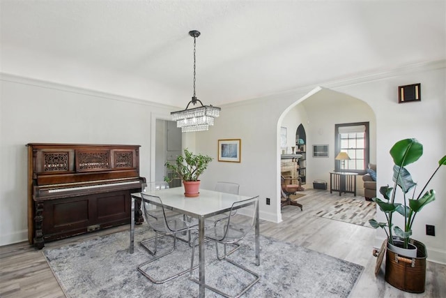 1912 NW 22nd St, Oklahoma City, OK 73106 - dining space featuring arched walkways, crown molding, light wood finished floors, and a chandelier