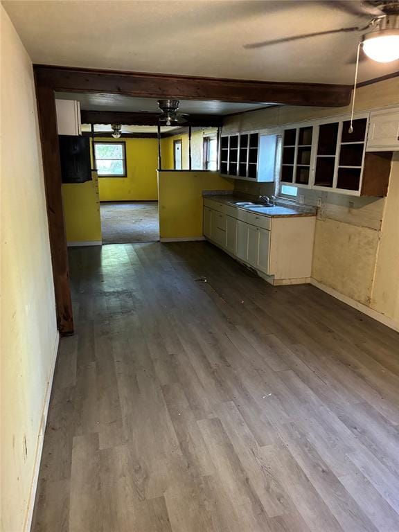 kitchen with a sink, baseboards, dark wood-style floors, and beam ceiling