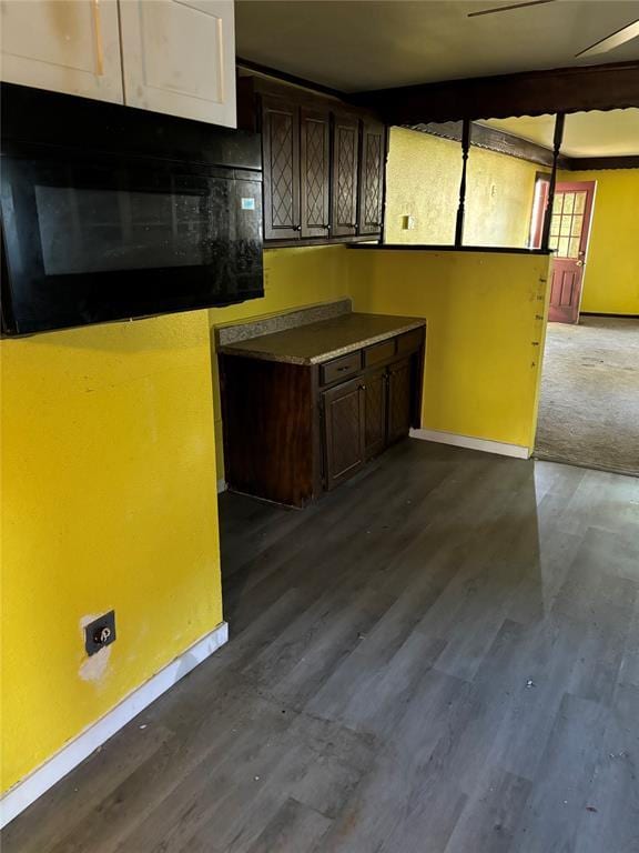 kitchen with dark wood-style flooring, dark brown cabinets, baseboards, and black microwave