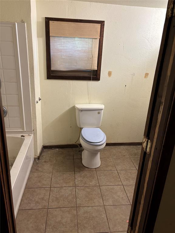 bathroom with baseboards, tile patterned flooring, and toilet