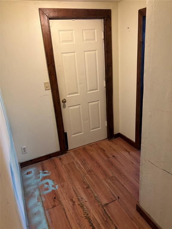 corridor featuring baseboards and wood finished floors