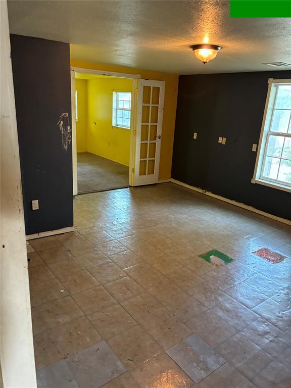 spare room featuring a textured ceiling, baseboards, and visible vents