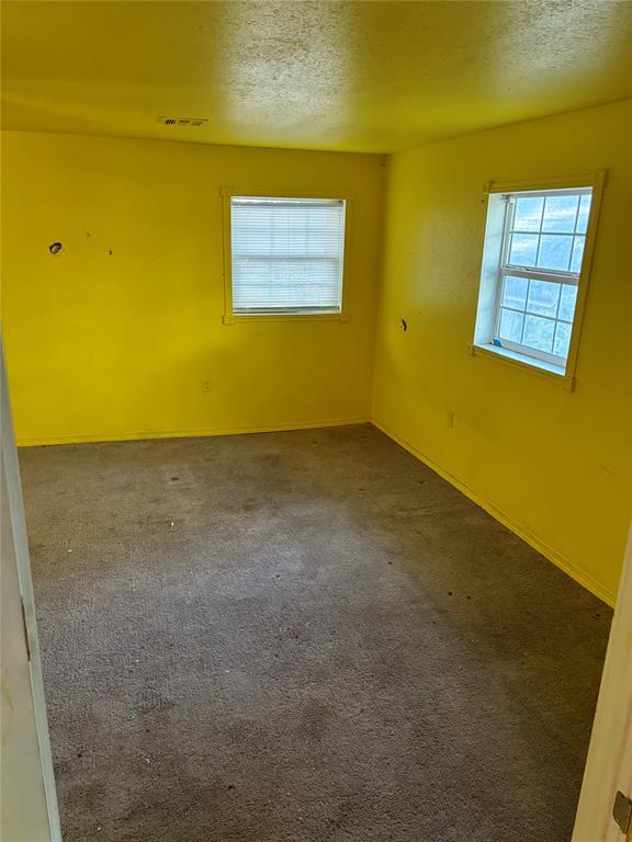 unfurnished room featuring carpet floors, a textured ceiling, and visible vents
