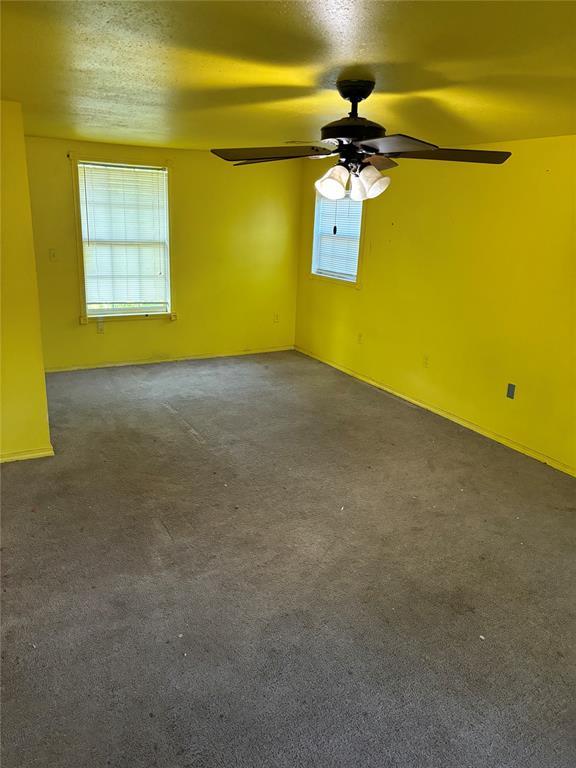empty room featuring a ceiling fan, a textured ceiling, baseboards, and carpet