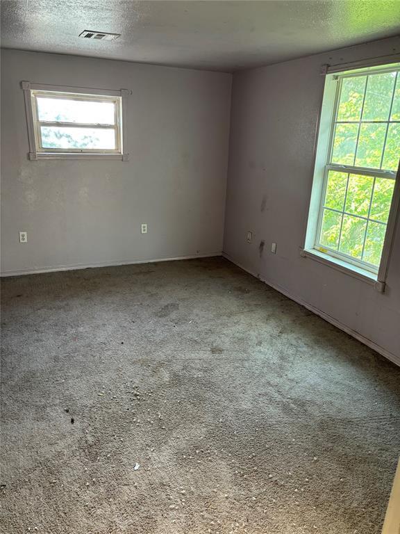 empty room featuring visible vents, a textured ceiling, and carpet