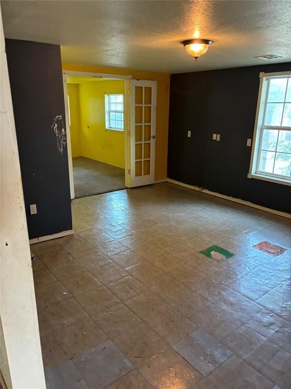 empty room featuring baseboards, a textured ceiling, and a wealth of natural light