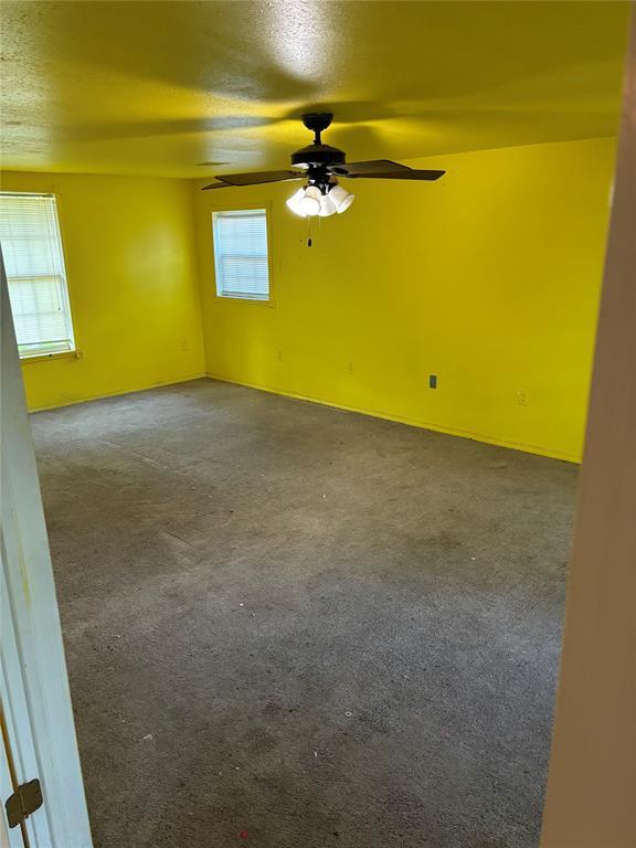 carpeted empty room featuring a ceiling fan and a textured ceiling