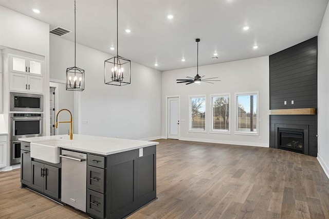 2217 Winter Creek Blvd, Blanchard, OK 73010 - kitchen with white cabinets, a sink, a fireplace, stainless steel appliances, and open floor plan
