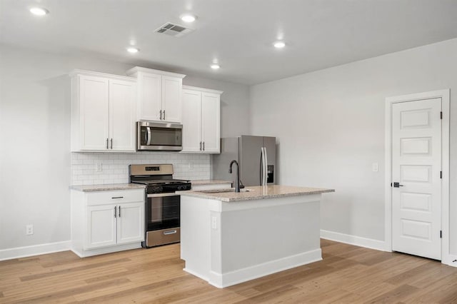 kitchen with light wood-style floors, appliances with stainless steel finishes, a center island with sink, and visible vents