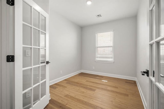spare room with visible vents, baseboards, wood finished floors, and french doors