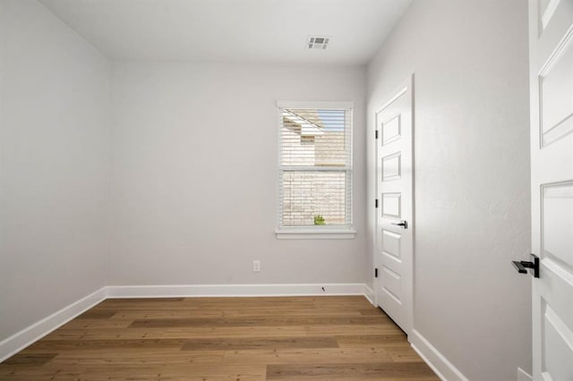 spare room with baseboards, visible vents, and wood finished floors