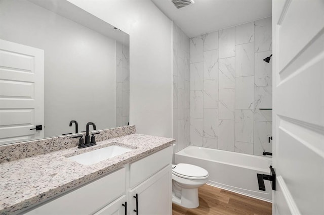 bathroom with visible vents, vanity, wood finished floors, toilet, and washtub / shower combination