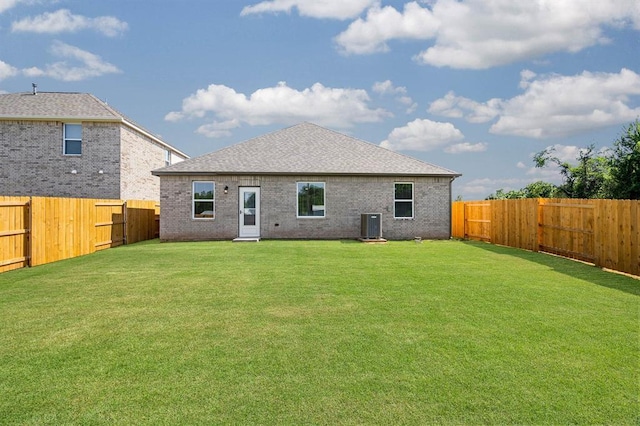 rear view of property with a yard, brick siding, a fenced backyard, and roof with shingles