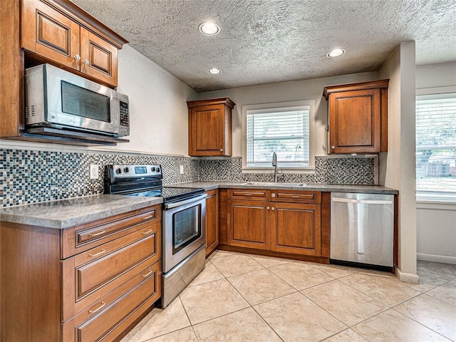 2429 Barclay Rd, Oklahoma City, OK 73120 - kitchen featuring appliances with stainless steel finishes, brown cabinetry, decorative backsplash, a textured ceiling, and recessed lighting