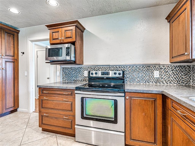 2429 Barclay Rd, Oklahoma City, OK 73120 - kitchen featuring stainless steel appliances, backsplash, a textured ceiling, brown cabinetry, and light tile patterned flooring