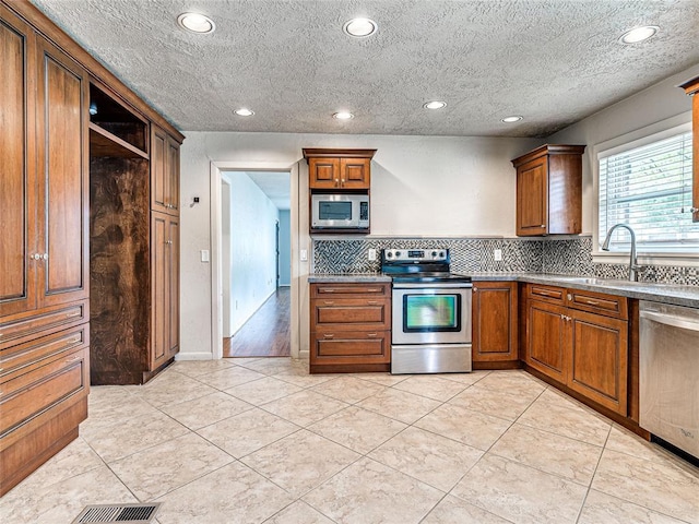 2429 Barclay Rd, Oklahoma City, OK 73120 - kitchen with stainless steel appliances, backsplash, open shelves, recessed lighting, and brown cabinetry