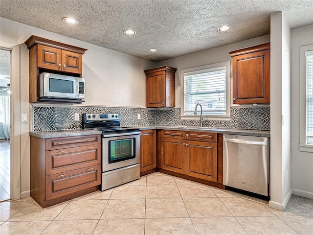 2429 Barclay Rd, Oklahoma City, OK 73120 - kitchen with stainless steel appliances, brown cabinets, tasteful backsplash, recessed lighting, and a textured ceiling