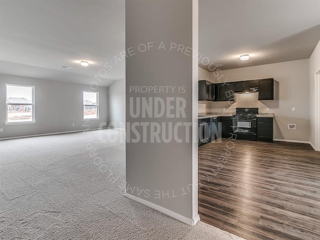 kitchen featuring dark wood-style flooring, light countertops, baseboards, black range with gas stovetop, and open floor plan
