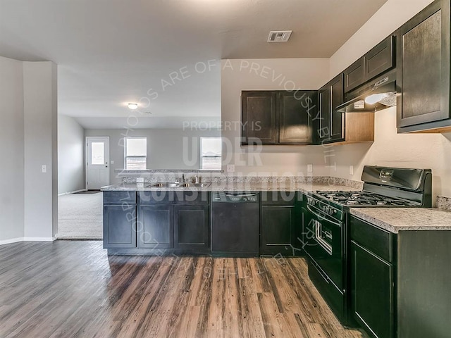 kitchen featuring dark wood-style flooring, a peninsula, under cabinet range hood, a sink, and black appliances