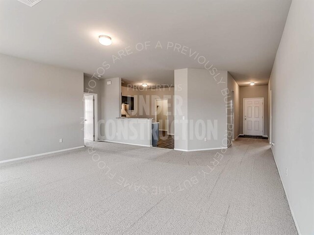 unfurnished living room featuring baseboards and light carpet