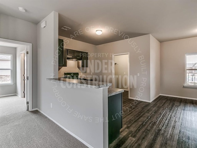 kitchen featuring visible vents, a peninsula, baseboards, stove, and dark wood-style floors