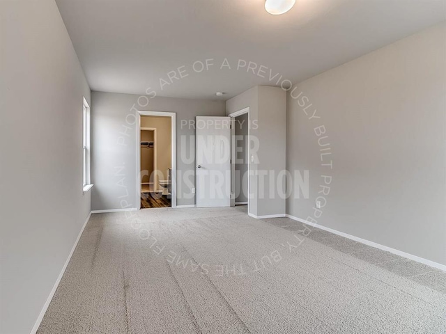 unfurnished bedroom with carpet floors, baseboards, and a spacious closet