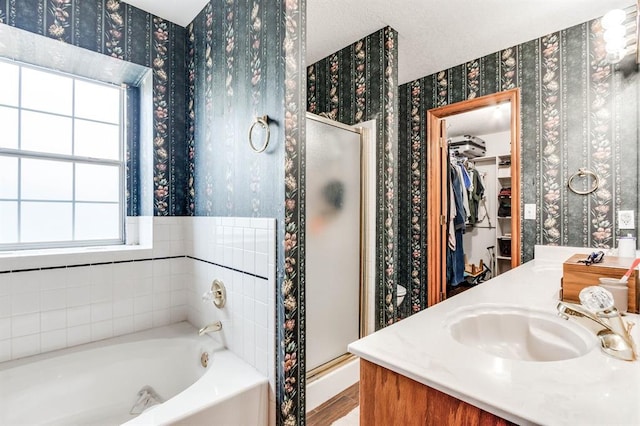 bathroom with wallpapered walls, a shower stall, a walk in closet, and a bath