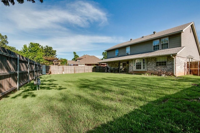 rear view of property featuring a yard, brick siding, a fenced backyard, and roof with shingles