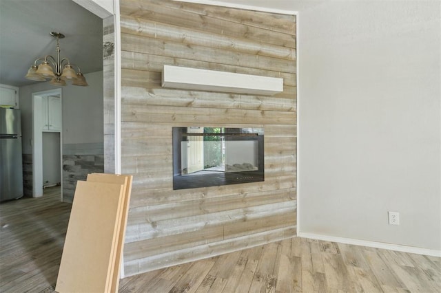 1662 NE 6th St, Moore, OK 73160 - unfurnished living room with a glass covered fireplace, a chandelier, wood finished floors, and baseboards