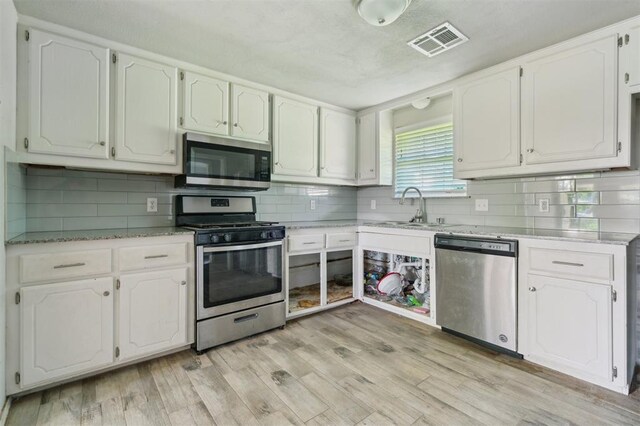 1662 NE 6th St, Moore, OK 73160 - kitchen featuring stainless steel appliances, a sink, white cabinets, and backsplash