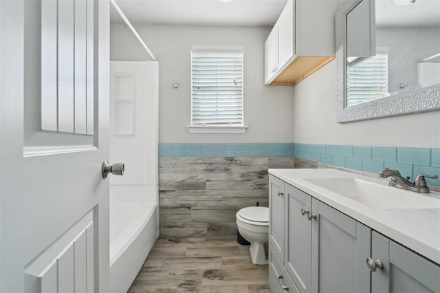 1662 NE 6th St, Moore, OK 73160 - bathroom with tile walls, plenty of natural light, toilet, vanity, and a wainscoted wall