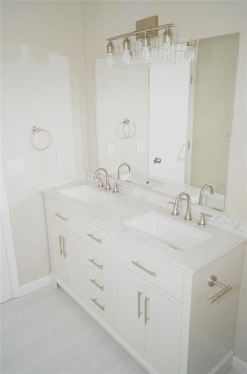 bathroom with double vanity, baseboards, and a sink