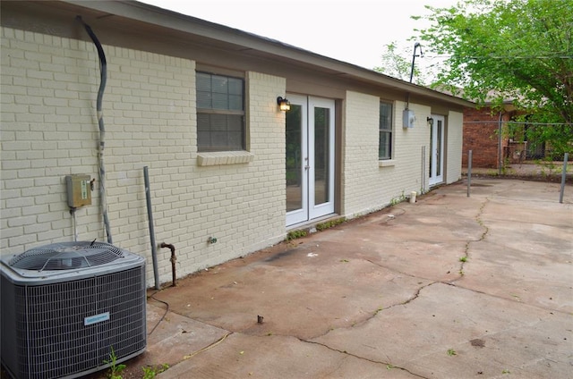 exterior space featuring french doors, a patio, central AC unit, and brick siding