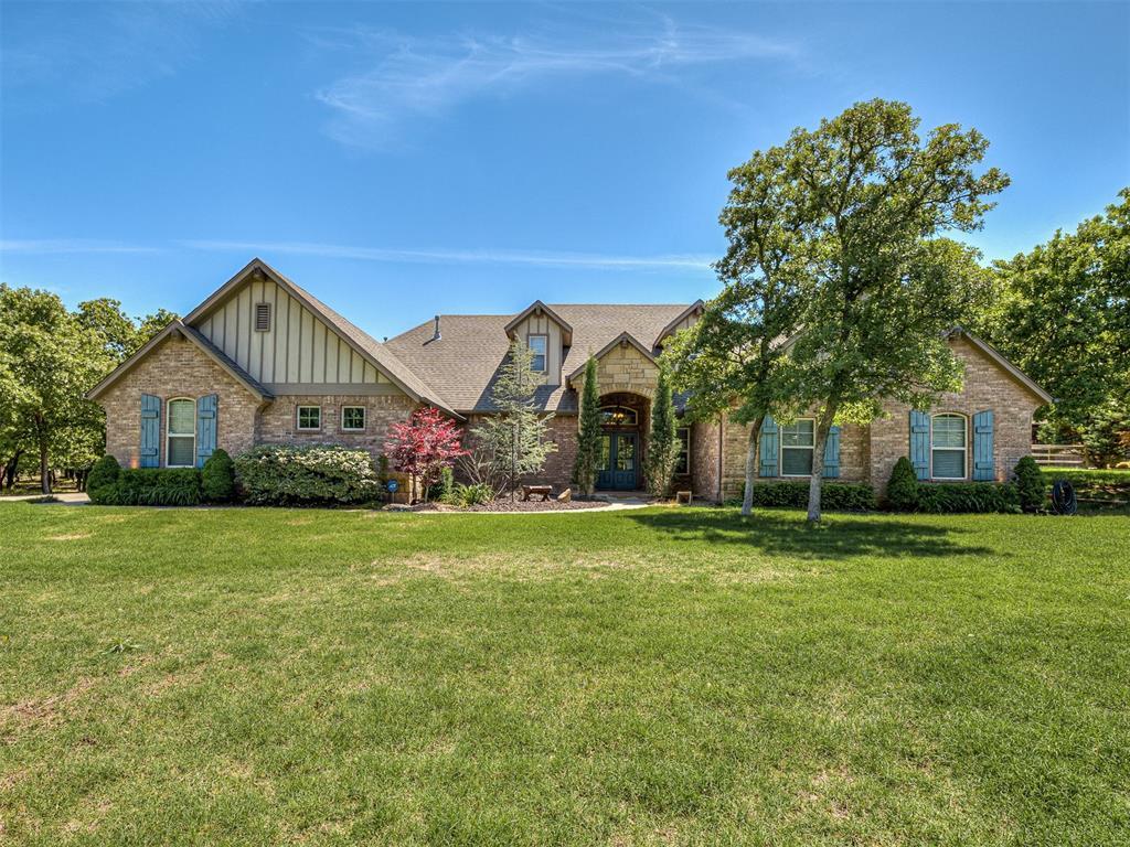 754 Breezy Hill Rd, Edmond, OK 73025 - view of front of home featuring board and batten siding, stone siding, and a front yard