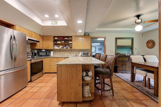 kitchen featuring open shelves, light brown cabinets, a kitchen breakfast bar, a raised ceiling, and appliances with stainless steel finishes