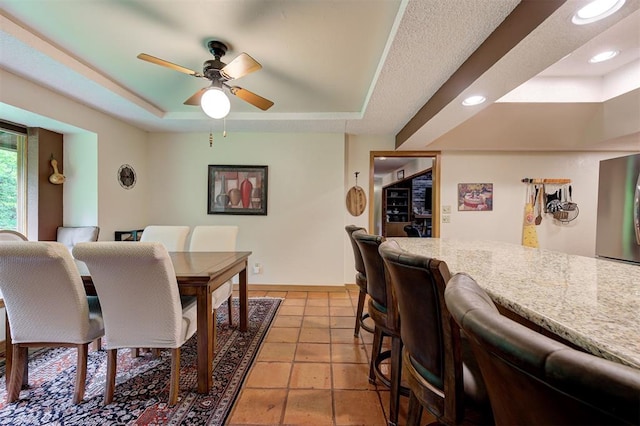 dining area with a ceiling fan, light tile patterned floors, a raised ceiling, baseboards, and recessed lighting