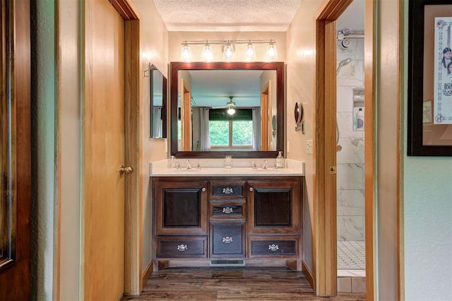 bathroom with double vanity, a sink, a marble finish shower, and wood finished floors