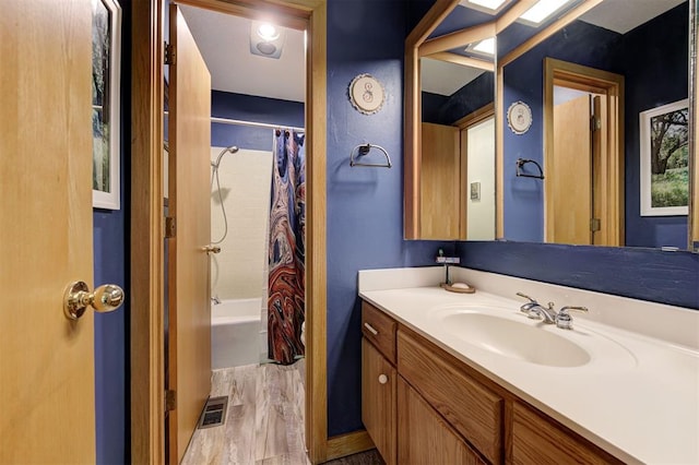 full bathroom with visible vents, wood finished floors, shower / tub combo, and vanity