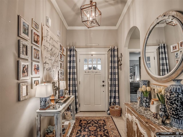 entrance foyer featuring visible vents, arched walkways, a notable chandelier, ornamental molding, and light tile patterned flooring