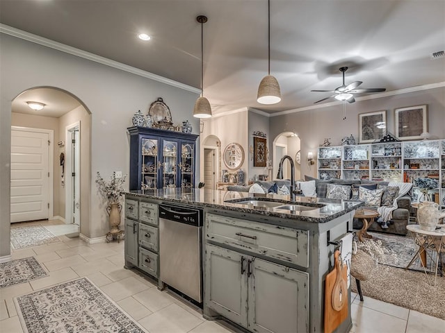 kitchen with stainless steel dishwasher, arched walkways, a sink, and dark stone countertops